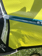 Duotone Super Hero SLS 4.5 2026 Kiteboard neongelb mit dunkelblauem Mast, Detailansicht auf Gras