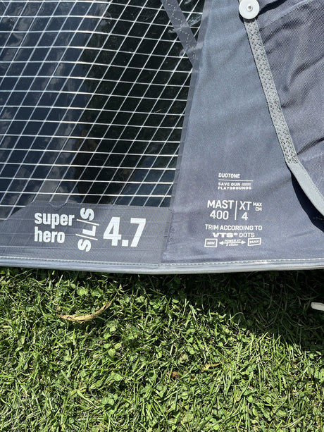 Duotone Super Hero SLS 4.7 Kite in Schwarz und Grau, Draufsicht auf Rasen mit Spezifikationen sichtbar