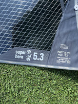 Duotone Super Hero SLS 5.3 Kiteboard mit Duotone-Logo, schwarzes Mesh-Design auf Gras, Draufsicht