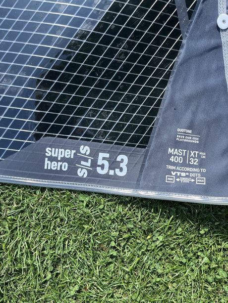 Duotone Super Hero SLS 5.3 Kiteboard mit Duotone-Logo, schwarzes Mesh-Design auf Gras, Draufsicht