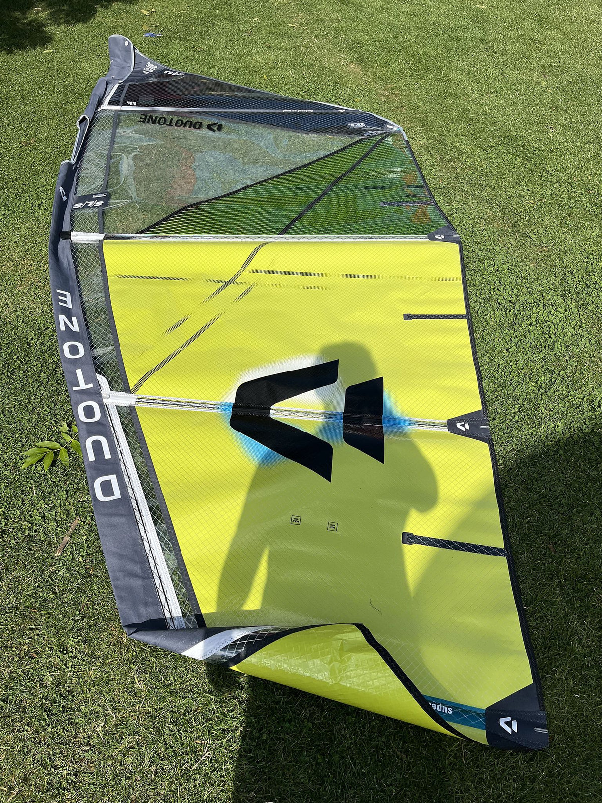 Duotone Super Hero SLS 5.3 2026 Kiteboard in Neongelb und Grau mit schwarzem Logo, Draufsicht auf Rasen