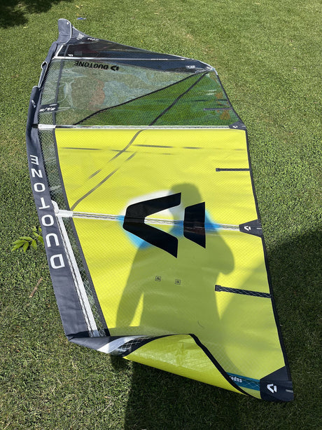 Duotone Super Hero SLS 5.3 2026 Kiteboard in Neongelb und Grau mit schwarzem Logo, Draufsicht auf Rasen