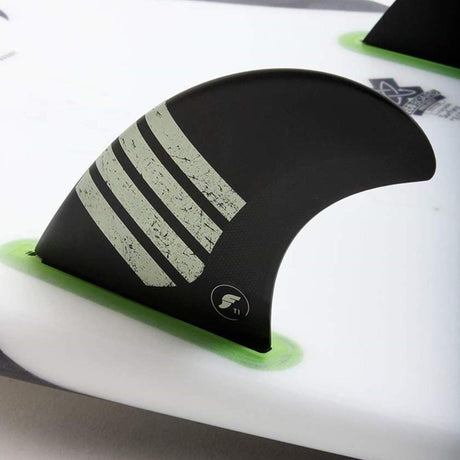 Futures Twin Tri Fin Set T1 Alpha mit schwarzer Basis, grünen Flossen und grau strukturiertem Design auf Surfboard