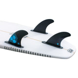 Futures AM1 Alpha Thruster Finnen Set, schwarze Kunststoffflossen mit blauen Akzenten auf weißem Surfboard, Frontalansicht
