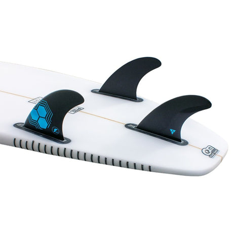 Futures AM1 Alpha Thruster Finnen Set, schwarze Kunststoffflossen mit blauen Akzenten auf weißem Surfboard, Frontalansicht