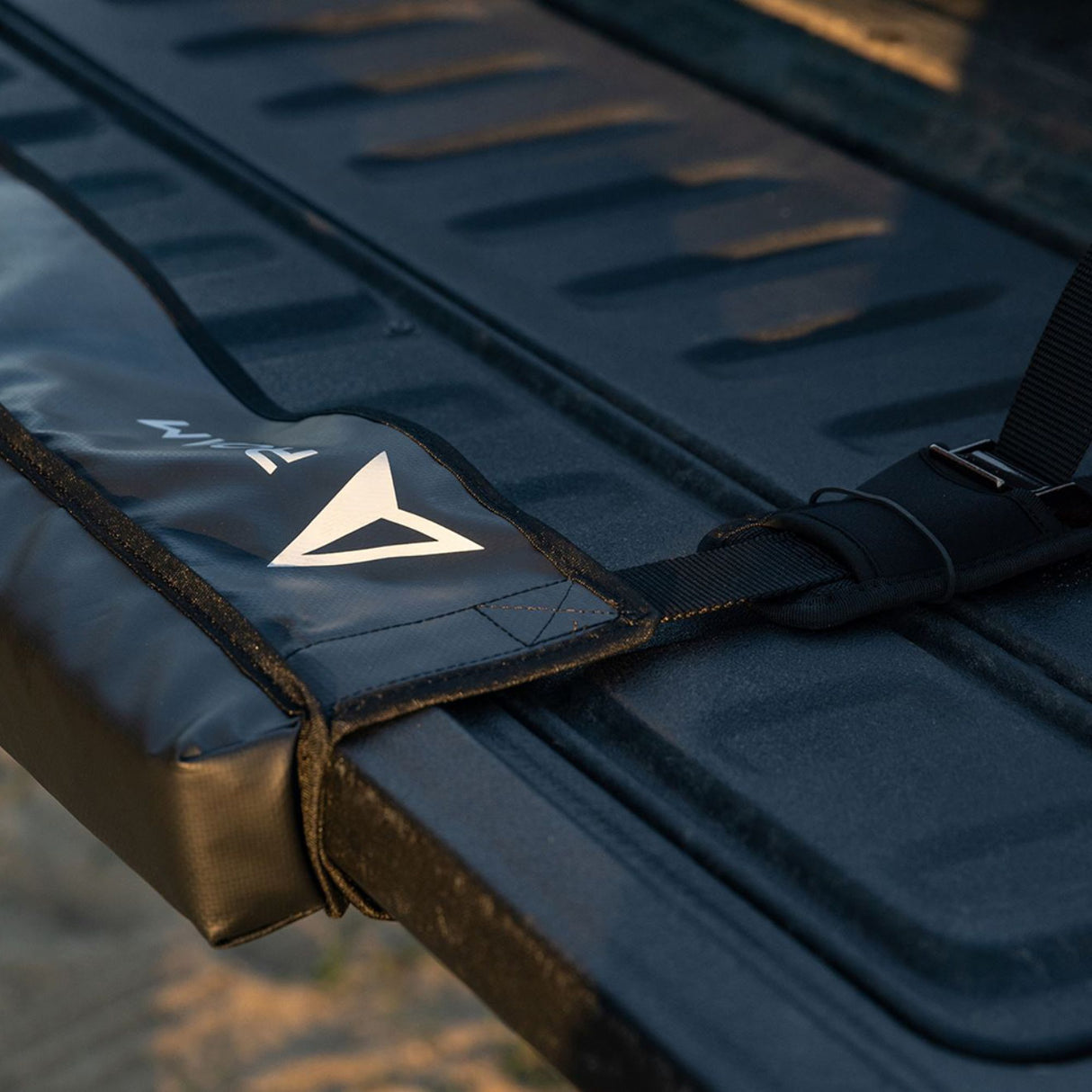 ROAM Pickup Tailgate Pad in Marineblau mit Logo, Nahaufnahme der gepolsterten Ladeflächen-Schutzauflage mit Befestigungsgurten