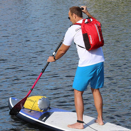 OverBoard wasserdichter Rucksack in Rot, getragen von Person beim Stand-up Paddling auf dem Wasser