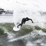 Surfer in schwarzer MDNS Neopren Haube Prime auf Surfboard in Welle, Frontansicht