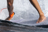 Roam Footpad Deck Grip Traction Pad 2-tlg in Orange, Füße auf Surfbrett im Wasser, Nahaufnahme