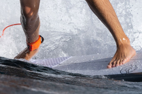 Roam Footpad Deck Grip Traction Pad 2-tlg in Orange, Füße auf Surfbrett im Wasser, Nahaufnahme
