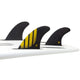 Futures Thruster Fin Set P4 Alpha, schwarz mit gelben Streifen, auf weißem Surfboard montiert