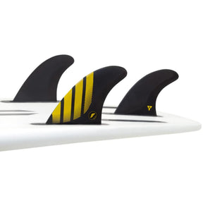 Futures Thruster Fin Set P4 Alpha, schwarz mit gelben Streifen, auf weißem Surfboard montiert