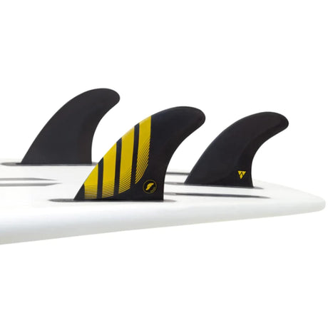 Futures Thruster Fin Set P4 Alpha, schwarz mit gelben Streifen, auf weißem Surfboard montiert