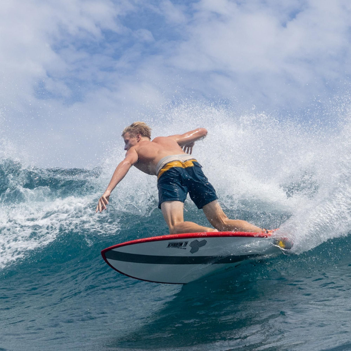 Channel Islands X-lite PodMod Surfboard rot-schwarz in Aktion im Wasser, Surfer in dynamischer Pose