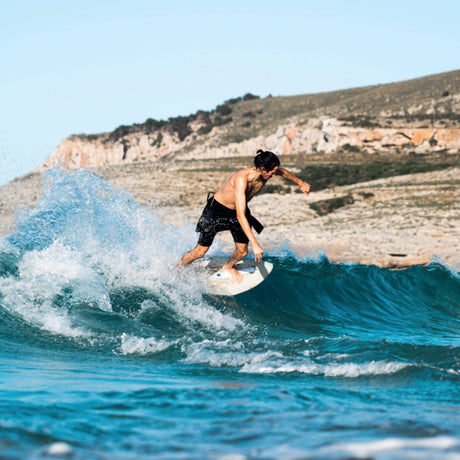 SkimOne EPS Epoxy Bambus Clover Skimboard in Weiß-Grün, Athlet beim Skimmen auf Welle