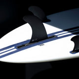 Roam Sidebite Fin Set Eduard Delpero Two Tab schwarze Flossen mit Two-Tab-Design auf blauweißem Surfboard