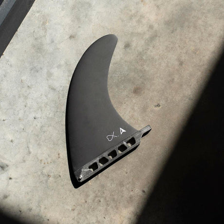 Roam Delpero Pro Single Fin, schwarze Surfboard-Finne mit US Box System, Draufsicht auf Betonuntergrund