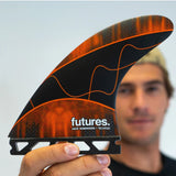 Futures Thruster Fin Set Jack Robinson Techflex, orange-schwarzes Design mit Wabenmuster, in Hand gehalten