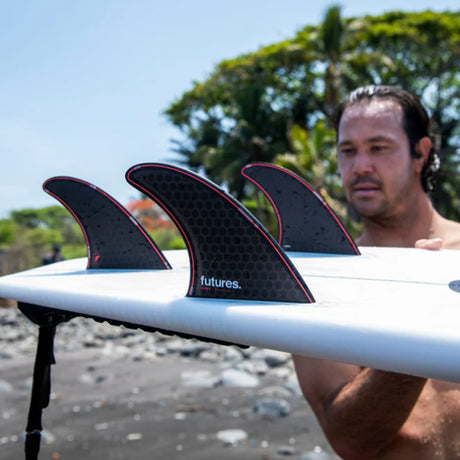 Futures Thruster Fin Set Jordy Smith Honeycomb, schwarze Flossen mit roten Kanten auf weißem Surfboard, Honeycomb-Material