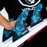 Futures Thruster Fin Set Jack Robinson Honeycomb in Blau mit Wabenmuster, in Hand gehalten über Surfbrett