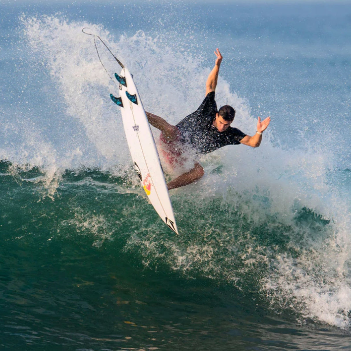 Futures Thruster Fin Set Jack Robinson Honeycomb, schwarze und weiße Finnen an weißem Surfboard in Aktion im Meer
