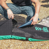 Sniper Bodyboard Rucksack Single Cover in Schwarz mit Grün, Person öffnet Reißverschluss am Strand