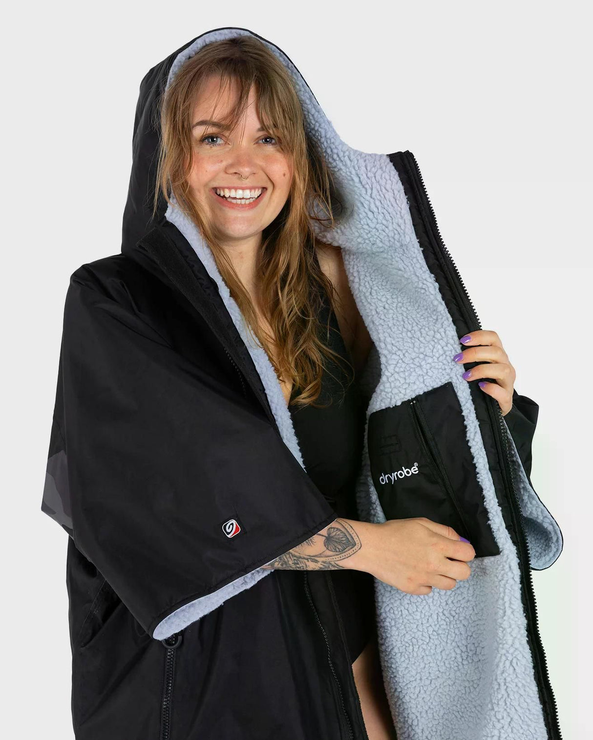 DRYROBE Advance Kurzarm in Schwarz mit hellgrauem Fleece-Futter, Frau trägt Umhang mit Kapuze, Vorderansicht