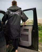 DRYROBE Advance Kurzarm in Schwarz, Rückansicht, Person trägt Robe neben Auto