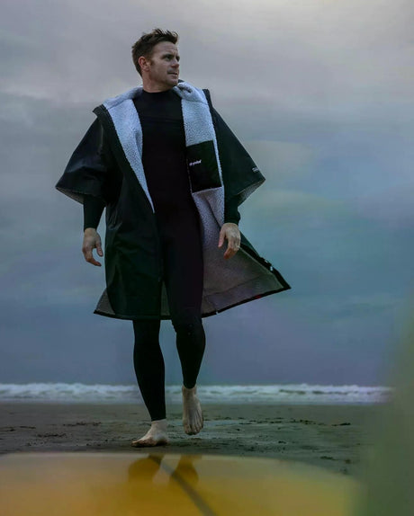 DRYROBE Advance Kurzarm in Schwarz mit hellblauem Fleece-Futter, Mann am Strand tragend