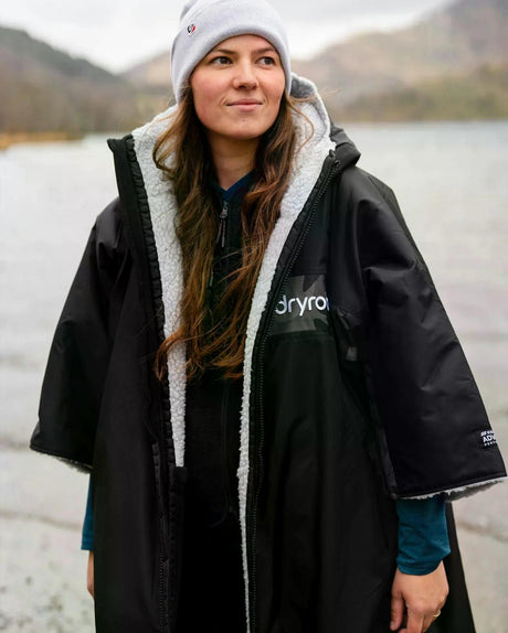 DRYROBE Advance Kurzarm schwarzer Umhang mit Sherpa-Futter, Frontansicht an einem See getragen