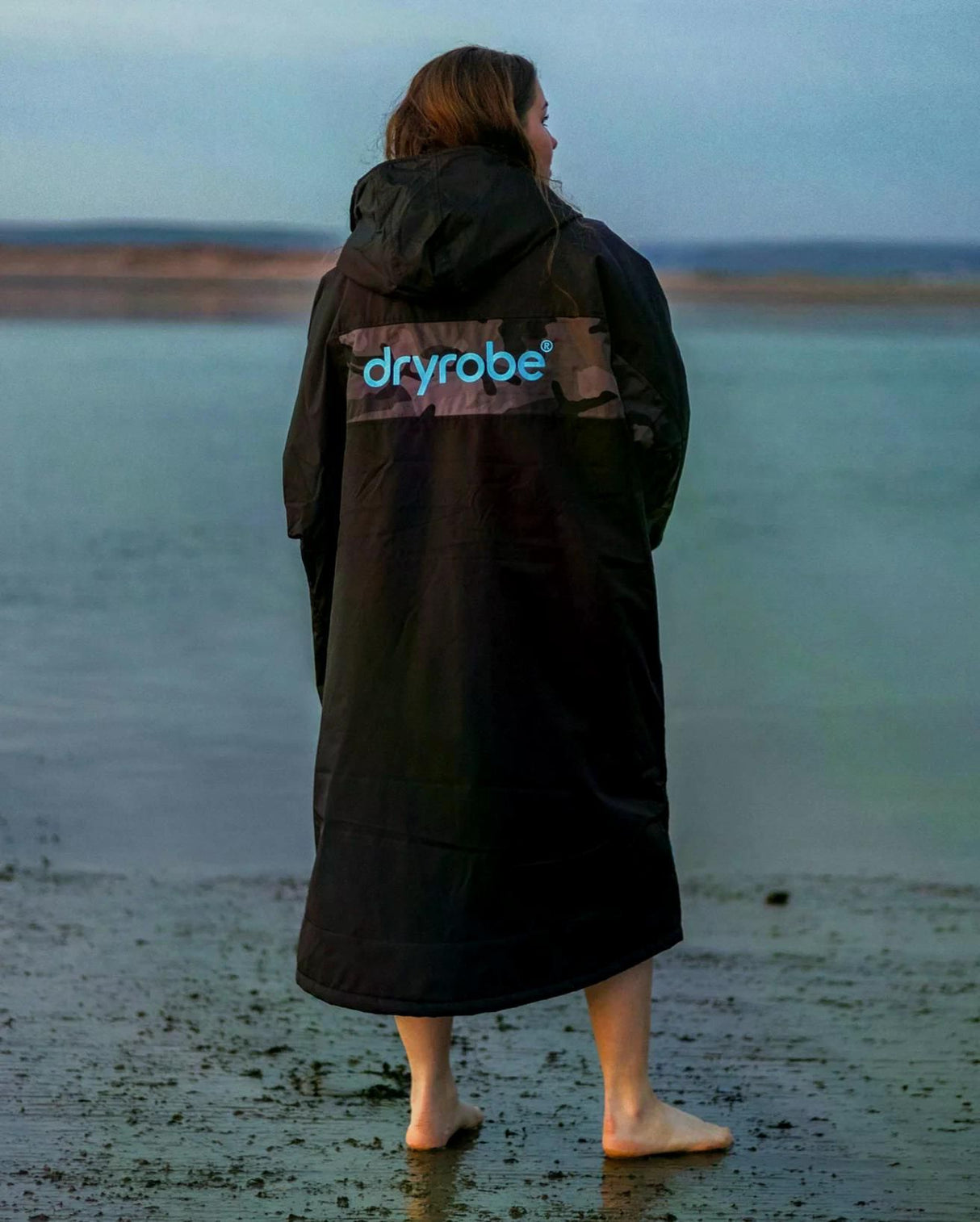 DRYROBE Advance Short Sleeve schwarze Umziehhilfe mit Kapuze, Rückansicht am Strand getragen