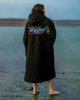 DRYROBE Advance Kurzarm in Schwarz, getragen am Strand, Rückansicht mit Logo-Print