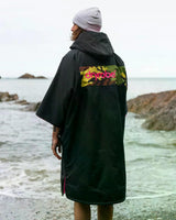 DRYROBE Advance Kurzarm in Schwarz mit Blumendruck, Rückansicht am Strand getragen, schnelltrocknende Materialien sichtbar