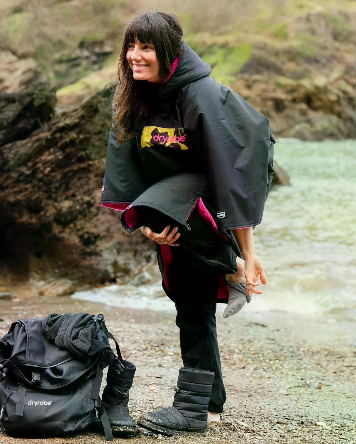 DRYROBE Advance Kurzarm in Schwarz mit pinken Akzenten, getragen am Strand, Frontalansicht
