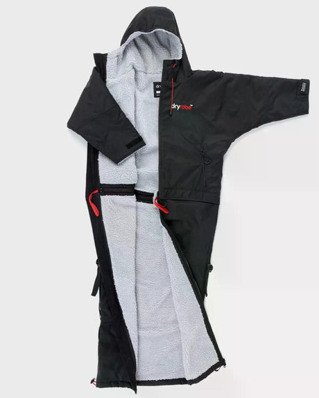 Dryrobe Adapt Mantel in Schwarz mit grauem Fleece-Futter, ausgebreitet von vorne, mit roten Riemen und funktionalen Details