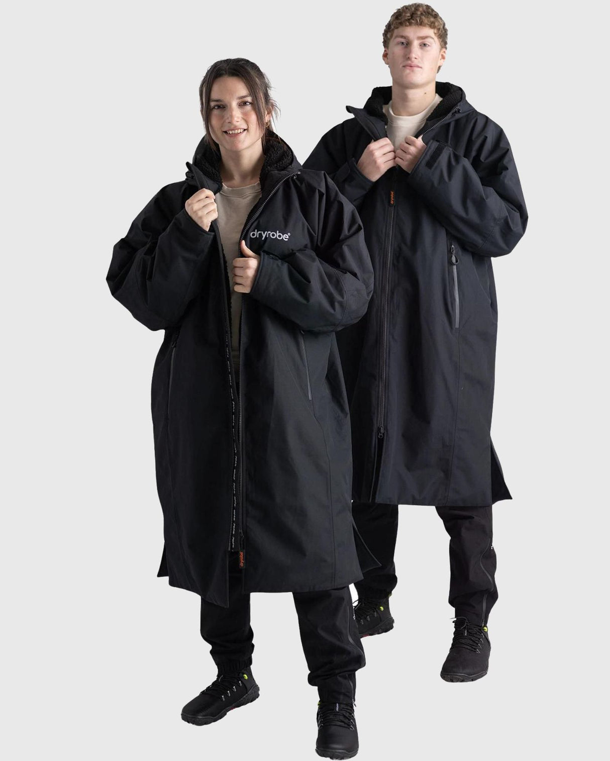 Dryrobe Nexus Long Sleeve in Schwarz, Umhang aus funktionalem Material mit Kapuze, von zwei Personen getragen