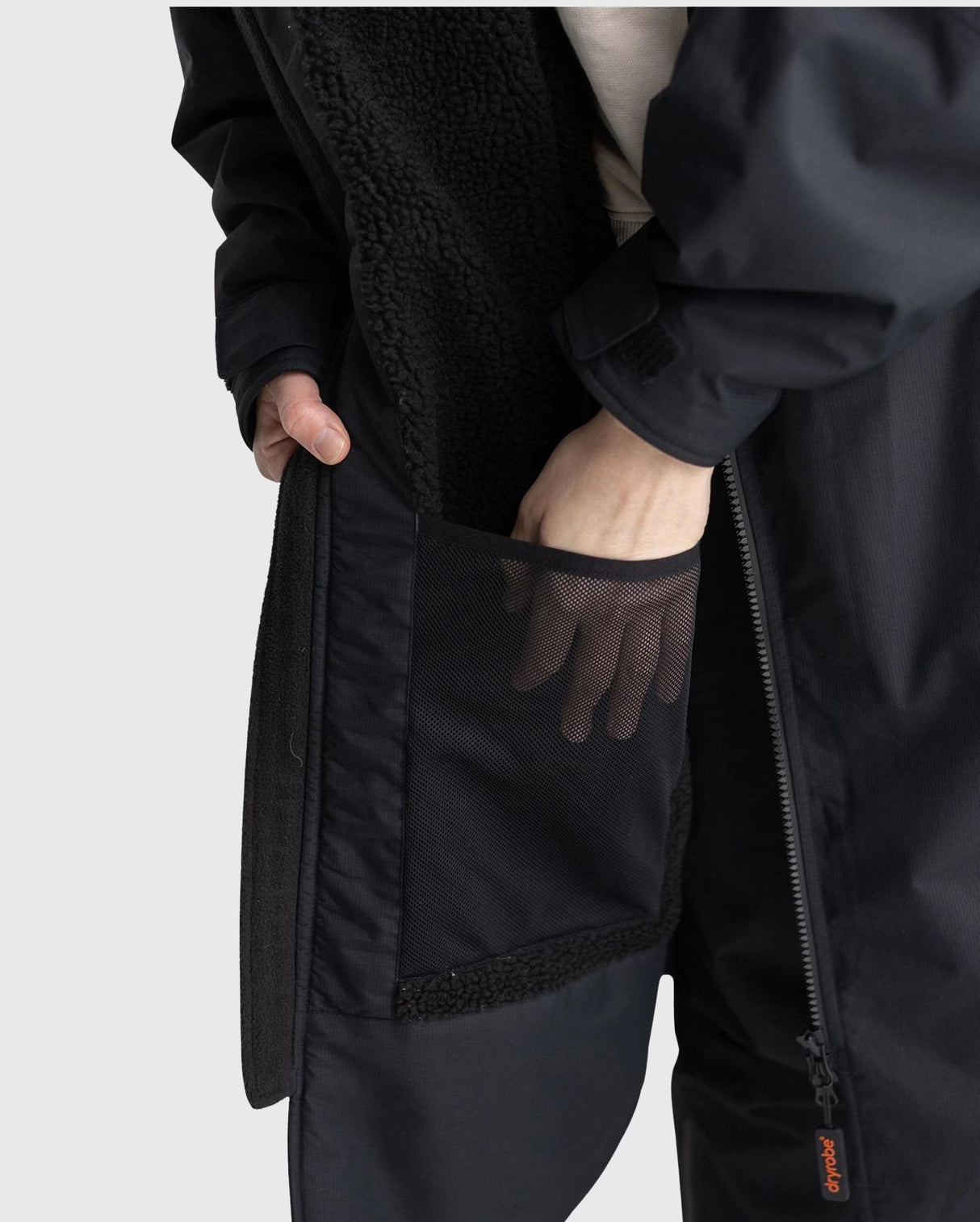 Dryrobe Nexus Langarm in Schwarz, Detailansicht der Tasche und Innenfutter aus Fleece, getragen von einer Person