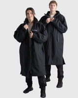 Dryrobe Nexus Long Sleeve schwarzer Bademantel mit Kapuze, Reißverschluss und Kängurutasche, getragen von zwei Personen