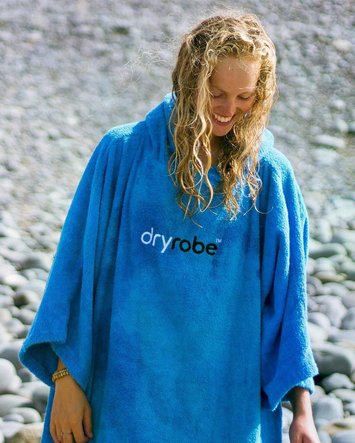 Dryrobe Handtuchmantel aus Bio-Baumwolle in Blau, getragen von einer Frau am Strand, Frontansicht