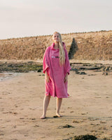 Dryrobe Handtuchmantel aus Bio-Baumwolle in Pink, getragen am Strand, Vorderansicht