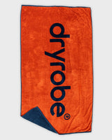 Dryrobe Strandtuch in Orange mit dunkelblauem Logo und Umschlag, Frontalansicht auf weißem Hintergrund