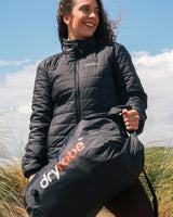 Dryrobe wasserdichter Drybag Packsack in Schwarz, von Frau in Natur getragen, robustes Nylon-Material