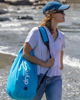 Dryrobe Drybag wasserdichter Packsack in Blau, über der Schulter getragen am Strand