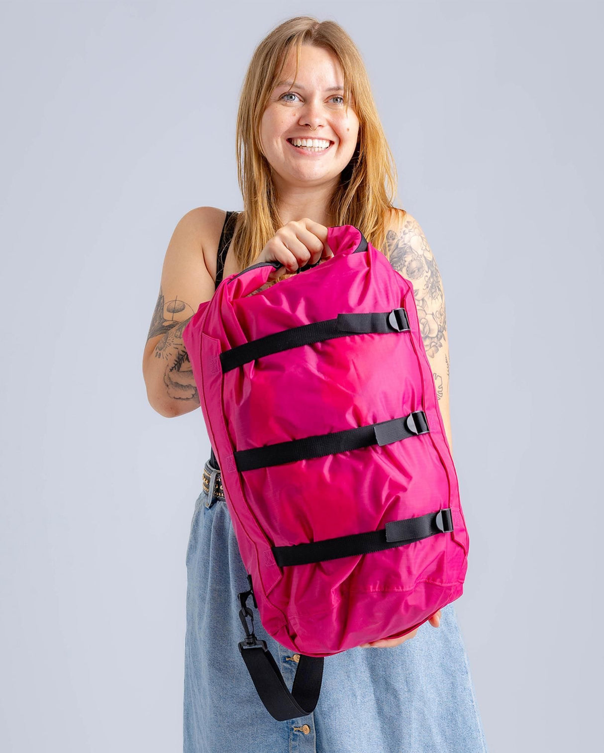 Dryrobe Drybag wasserdichter Packsack in Pink mit schwarzen Verschlussgurten, von Frau gehalten