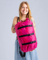 Dryrobe Drybag wasserdichter Packsack in Pink mit schwarzen Verschlussgurten, von Frau gehalten