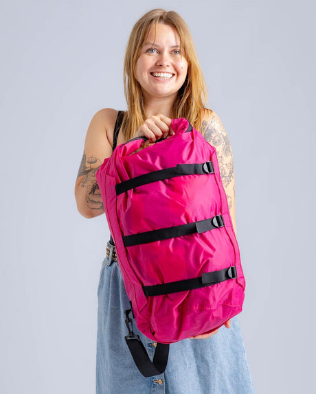 Dryrobe Drybag wasserdichter Packsack in Pink mit schwarzen Verschlussgurten, von Frau gehalten