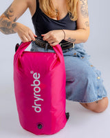 Dryrobe Drybag wasserdichter Packsack in Pink mit Rollverschluss, von Person gehalten
