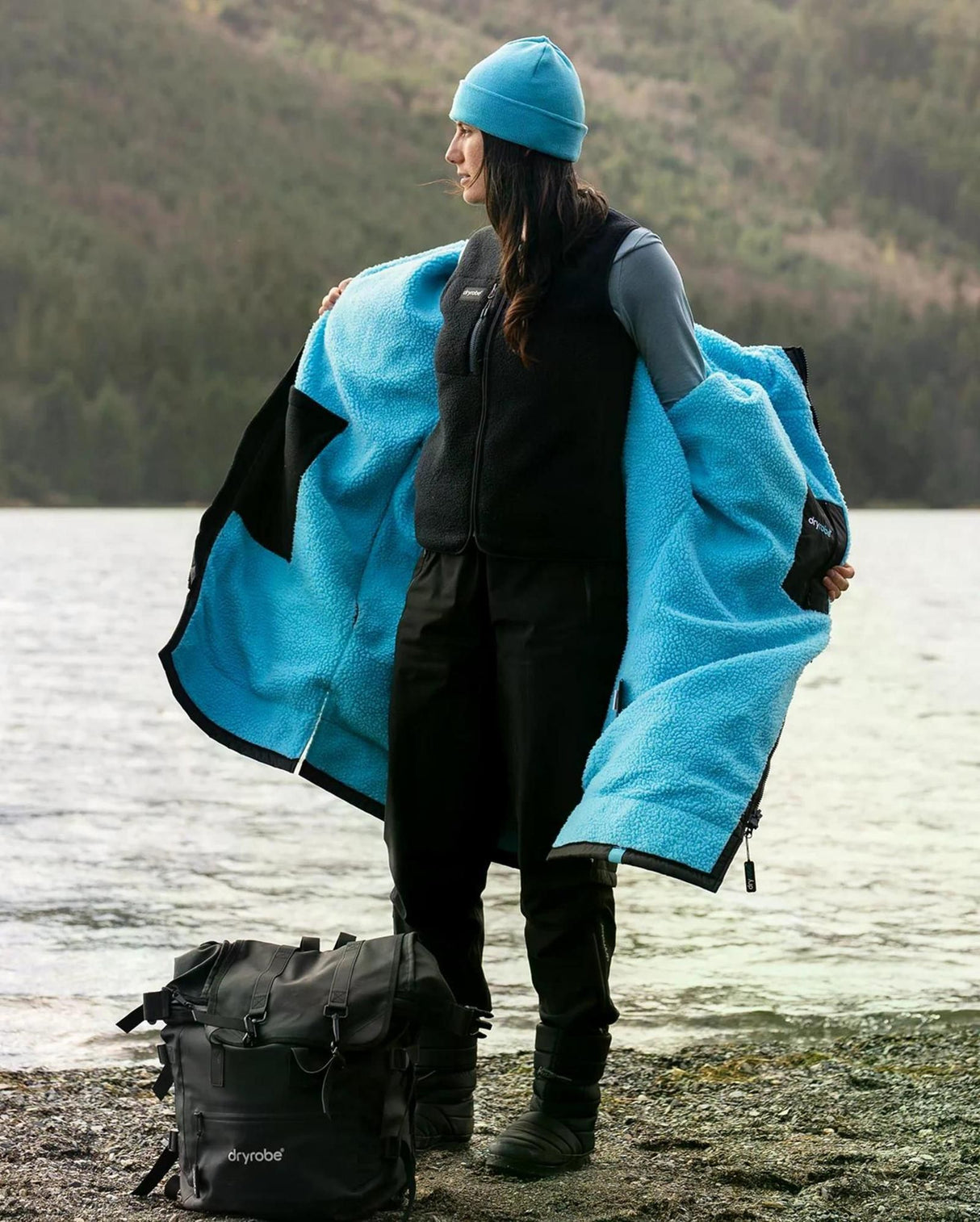 Dryrobe Thermo Weste in Blau-Schwarz, getragen von hinten am See, mit Kapuze und offenen Seiten, Funktionsweste aus Fleece