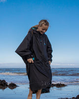 Dryrobe Advance Long Sleeve Kids schwarzer Umzieheranzug mit Kapuze, Kind am Strand