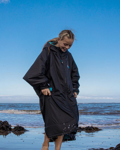 Dryrobe Advance Long Sleeve Kids schwarzer Umzieheranzug mit Kapuze, Kind am Strand